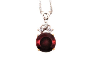 Round ruby and diamond pendant in white gold.